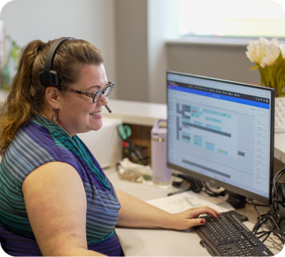 Customer Service Representative smiling and typing on computer keyboard